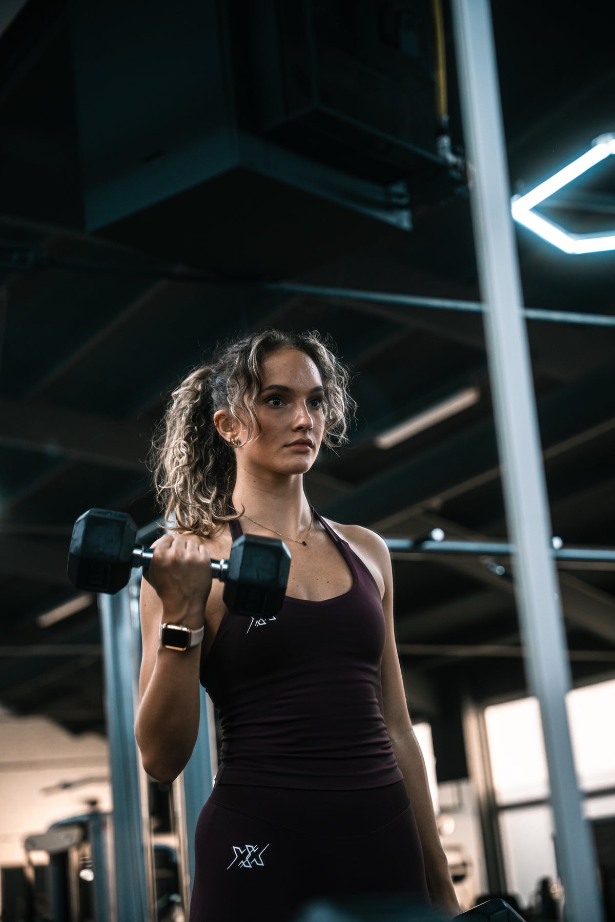 Atlete in de Extreme Halter Top in Dark Coffee doet een bicepscurl met dumbbell